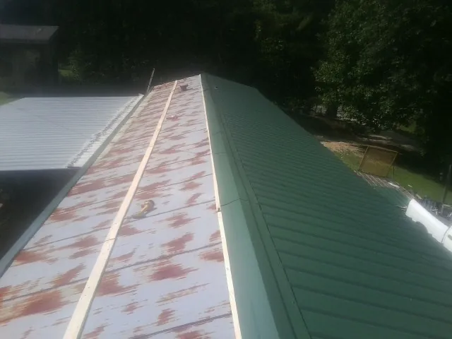 Old rusted panels beside newly installed green metal roofing — Wind Damage Roof Repair by Roofing Brothers in North Franklin