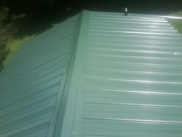 New green metal panels meeting at the ridge of a roof — Flat Roof Repair work by our crew in North Franklin