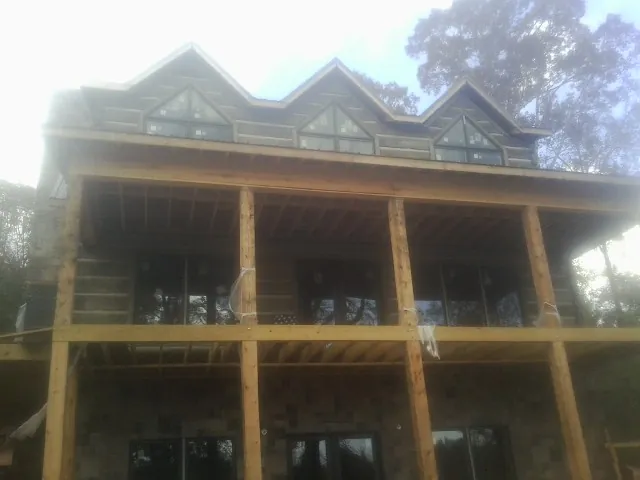 Dormers and porch framing on a large log home under construction — Roof Coating work by our crew in North Franklin