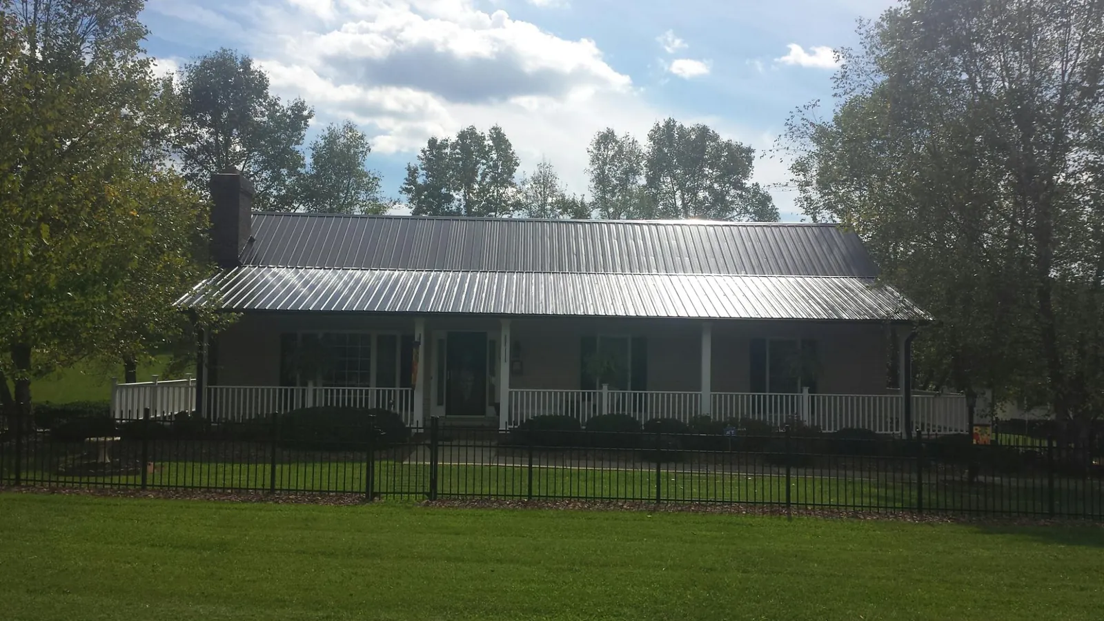 Gray metal roof on a brick ranch with a full width front porch — Gutter Guard Installation work by our crew in North Franklin