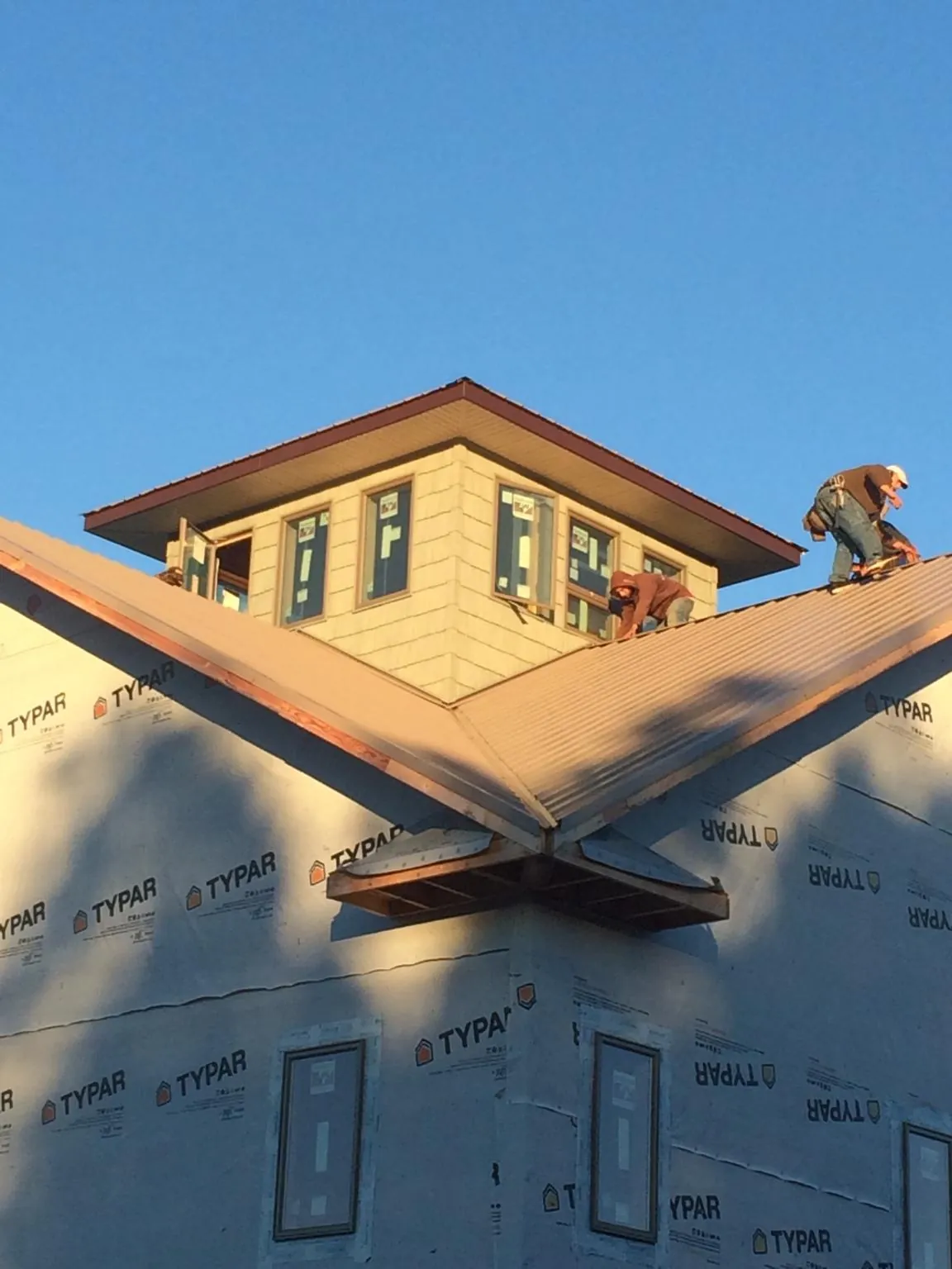 Roofers working around a rooftop cupola on a new metal roof at sunset — Roof Waterproofing in North Franklin by Roofing Brothers